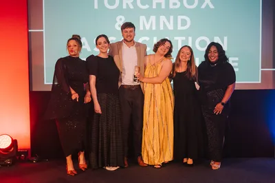 Siobhan, Jay, Iona and Rachel collecting the award at the UK Agency Awards. The team stand together on stage in front of the event backdrop, smiling and holding the trophy under the stage lights.
