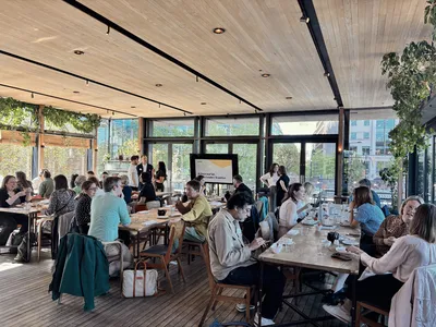 A full room at the Lighterman with attendees seated at tables, eating breakfast and networking during the AI Show and Tell event.