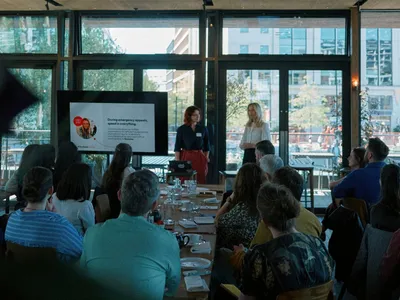 Iona and Natasha from the DEC speak to an audience, standing in front of a presentation screen during their session.