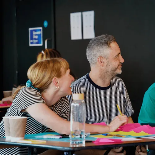 Miles, Rachel and Dan look to their left as they chat during a team workshop