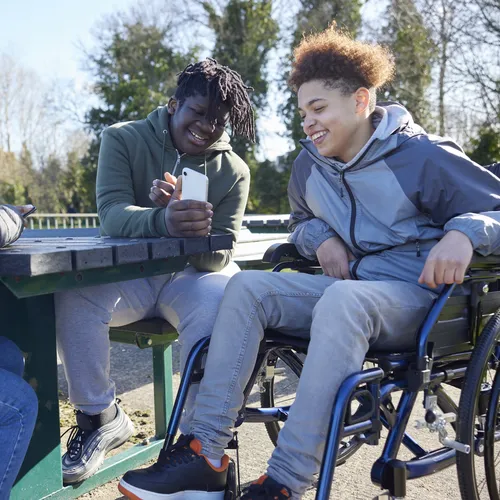 Boy in wheelchair chatting to friends and looking at a phone