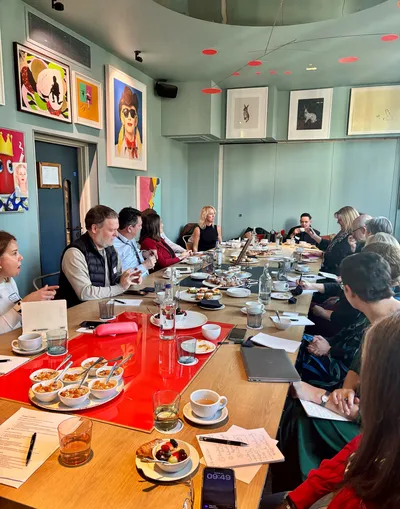 Charity leaders gathered around a table in discussion during a breakfast event.