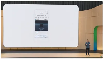 A presentation stage where a large screen shows a mobile Google search result for "how do black holes affect...". The "AI Overview" features an interactive 3D visual of a black hole warping a grid, complete with a adjustable "Black Hole Mass" slider and explanatory text. A presenter stands on stage to the right of the screen.