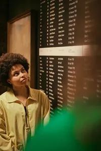 A woman looking at a board with lots of names of captains and owners of ships that sailed from London