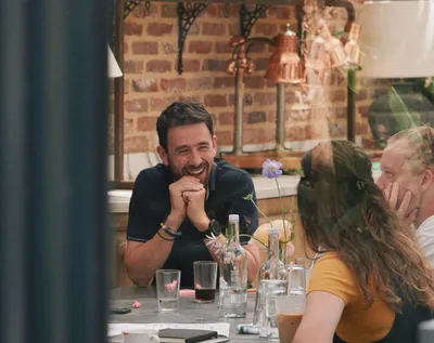 James laughs and chats with Marnie and Olly during a company event