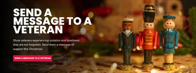 Festive Christmas background with three wooden toy soldier and sailor figurines in uniform, standing on a decorated table. Text reads: 'SEND A MESSAGE TO A VETERAN. Show veterans experiencing isolation and loneliness they are not forgotten. Send them a message of support this Christmas.' Pink button reads: 'SEND A MESSAGE TO A VETERAN'."