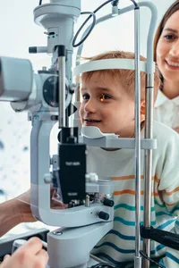 A child having an eye examination, with an adult looking on.