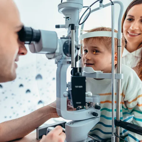 A child having an eye examination, with an adult looking on.