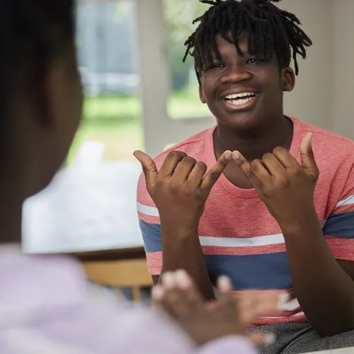 Two young people having a conversation using sign language at home.