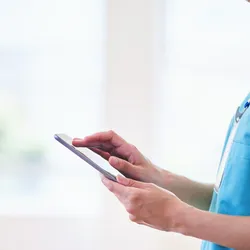 A medical professional uses an iPad.