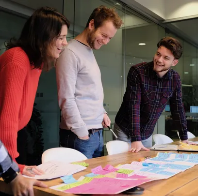 The team stand over the table to read coloured sticky notes