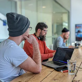 Kyle, Dan and Will working in the Bristol office with team members also on a zoom call on the screen