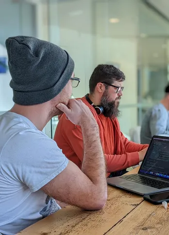 Kyle, Dan and Will working in the Bristol office with team members also on a zoom call on the screen